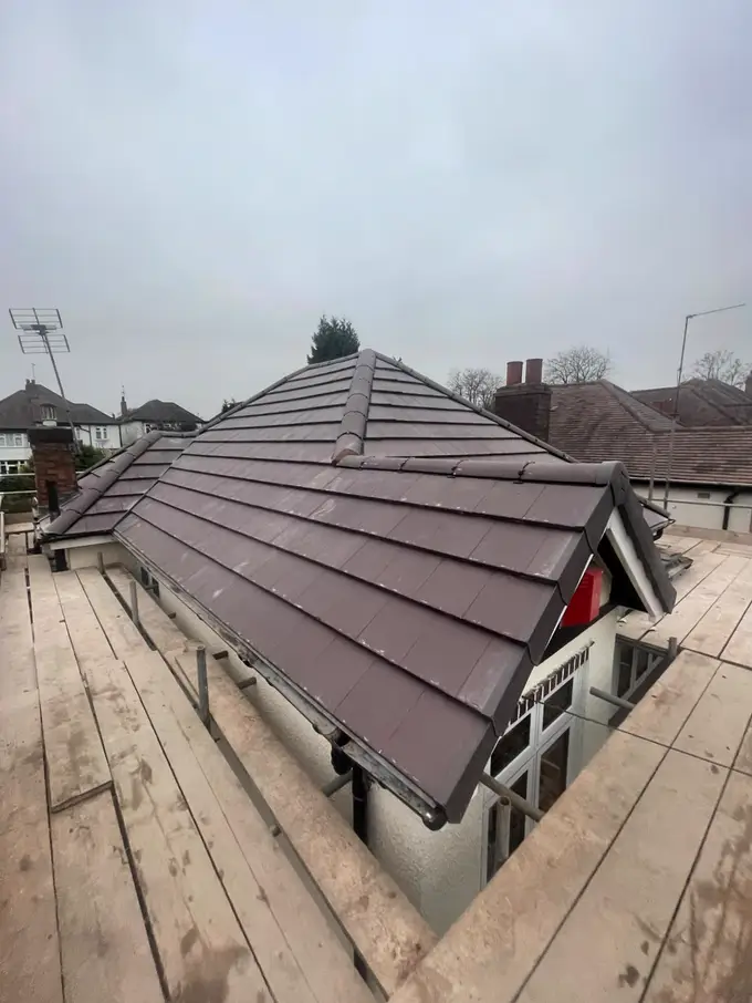 Newly tiled hipped roof with finished ridge and hip lines, seen from the scaffold
